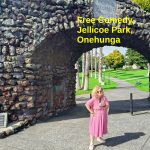 Tessa, mic in hand, stands in front of the memorial arch at Jellicoe Park, Onehunga