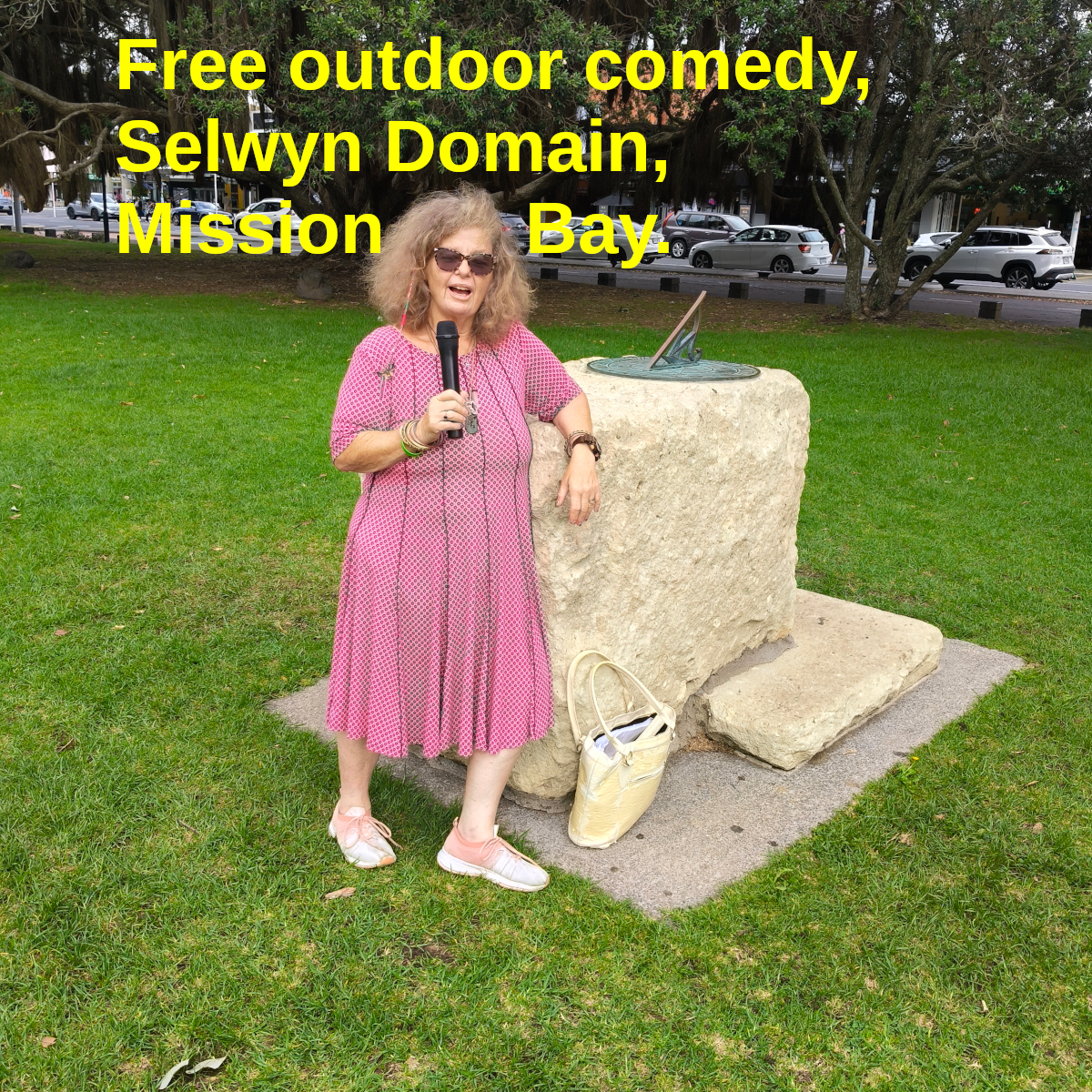 Tessa, mic in hand, stands in front of the sundial in Selwyn Domain, Mission Bay.